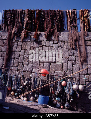 Fischernetze hängen über eine Mauer am Hafen Sennen Cove Cornwall UK Stockfoto