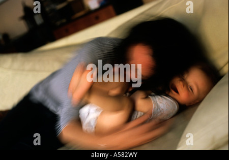 Mutter und ihre kleine Tochter zusammen zu spielen und Lachen auf einem Sofa. Stockfoto