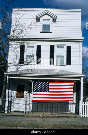 Dreistöckigen weißen Fachwerkhaus mit großen amerikanischen Flagge hängen, Veranda Stockfoto