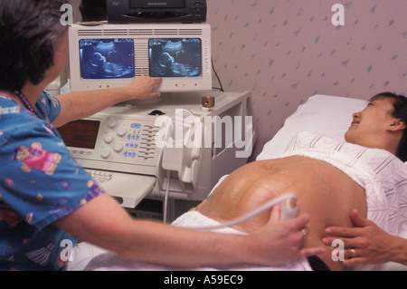 Ärztin, Ultraschall-Test für Schwangere Asiatin mit Fötus auf Bildschirmen geben Stockfoto