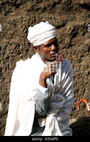 Lalibela, Äthiopien, Priester hält ein Kreuz vor einem der den Fels gehauenen Kirchen Stockfoto