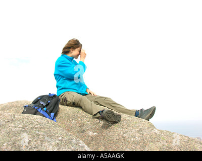 Junge Frau mit Rucksack sitting on Top of Mountain Rock nehmen Foto Stockfoto