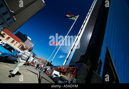 Ein südafrikanische Mann zu Fuß passieren einen Wolkenkratzer in der Stadt Johannesburg Stockfoto