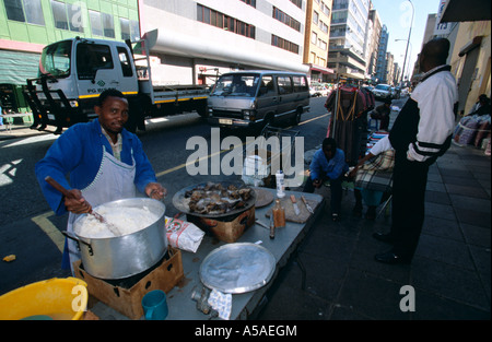 Ein Kreditor rühren einen Topf mit Essen in seinem am Straßenrand Stall in Johannesburg Stockfoto