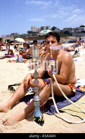 Mann Rauchen Wasserpfeife (Shisha) am öffentlichen Strand, Jbeil, Beriut, Libanon Stockfoto