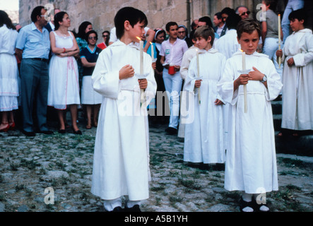 Spanien, Caceres, Trujillo, Fronleichnam-Tag. Chor Jungen Straße Prozession in weißen Gewändern, verlassen die Kirche und tragen Kerzen nach dem Feiertagsgottesdienst. Stockfoto