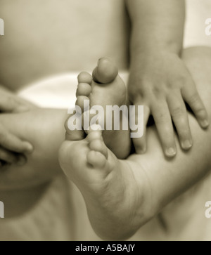Säugling Baby halten und Hände und Füße zu entdecken. Stockfoto