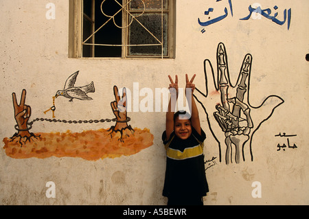 Junge zeigt Frieden Zeichen gegen Graffiti an der Wand, Flüchtlingslager Shatila, Beirut, Libanon Stockfoto