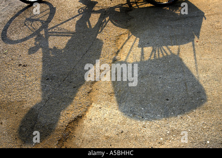 Schatten Sie auf der Straße von Fahrer und Fahrrad-Rikscha Kanchanaburi Thailand Stockfoto