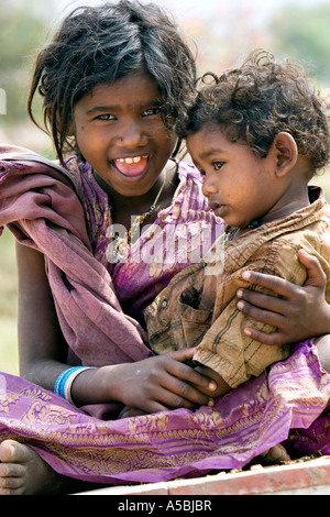 Niedrigere Kaste indische Mädchen Schneidersitz sitzen mit ihrer Babyschwester auf dem Schoß Stockfoto