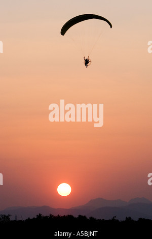 Silhouette Profil des Mannes mit einem Motorschirm in Südindien in den Abendstunden Sonne im Hintergrund Einstellung Stockfoto