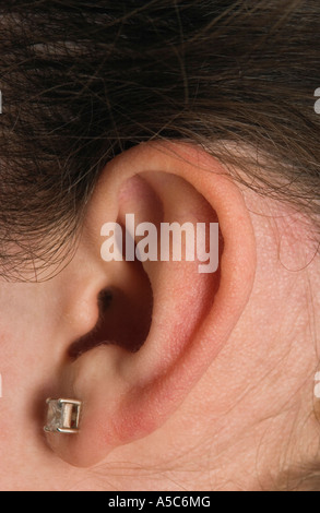 Detail des Mädchens Ohr mit kleine Ohrstecker und dunkle Haare Stockfoto