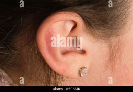 Detail des Mädchens Ohr mit kleine Ohrstecker und dunkle Haare Stockfoto