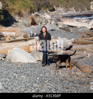 Frau zu Fuß Hund am Strand mit Treibholz in der Nähe von Victoria Vancouver Island Kanada Stockfoto