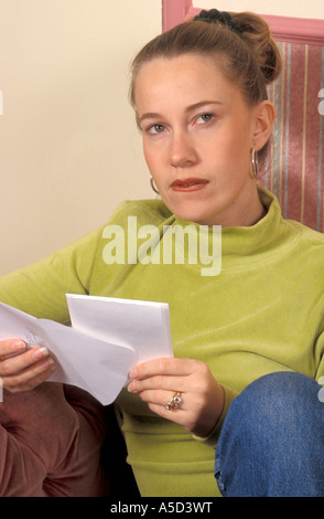 junge Frau mit Blick auf Gesicht besorgt, da sie Brief öffnet Stockfoto