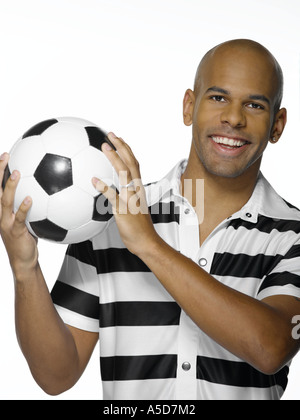 Junger Mann, der Fußball, hält lächelnd Stockfoto