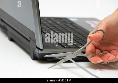 Menschliche Hand schneiden Telefonkabel auf Laptop-computer Stockfoto