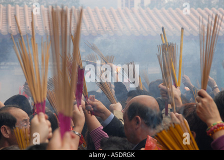 Gläubigen brennende Räucherstäbchen während Lunar New Year Feiern im Wong Tai Sin Tempel, Kowloon zu halten. Hongkong, China Stockfoto