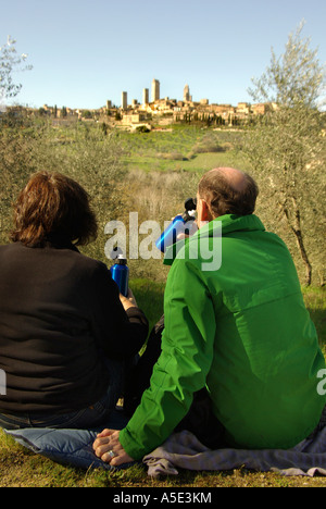 San Gimignano Toskana Italien paar mit einem Picknick in einem Olivenhain mit Blick auf die vielen Türme vertikal Stockfoto