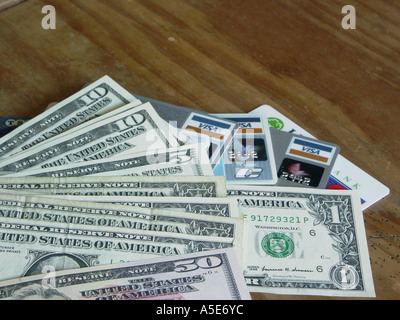Amerikanische Dollarnoten oder Noten verschiedener Konfessionen zusammen mit Kredit- oder EC-Karten auf dem Tisch. Stockfoto