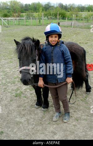 schwarze Mädchen mit Shetland-Ponys, die mit ihrer Mutter fahren zu lernen Stockfoto