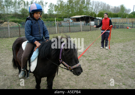 schwarze Mädchen mit Shetland-Ponys, die mit ihrer Mutter fahren zu lernen Stockfoto