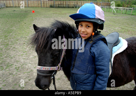 schwarze Mädchen mit Shetland Pony reiten lernen Stockfoto