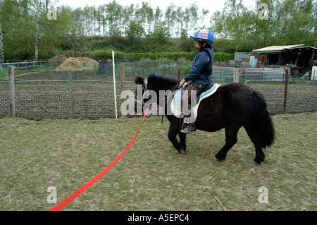 schwarze Mädchen mit Shetland Pony reiten lernen Stockfoto