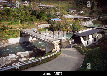 Beschädigte Straße zur Brücke und das Gebäude hat wegen unter Schnitt durch den Fluss gestürzt. Shiiba, Kyushu, Japan. Stockfoto