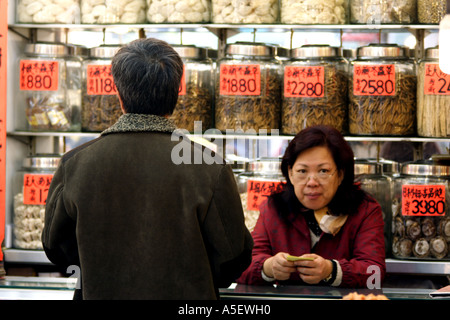 Hong Kong, Kowloon, Apotheke, Frau traditionelle getrocknet waren und die östliche Medizin auf dem Markt, China Stockfoto