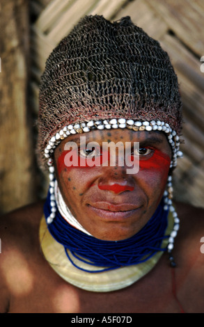 Huli-Frau aus Tari in Papua-Neuguinea mit Kopfbedeckung, verziert mit Zehenmuscheln und blauen Perlen über einem Perlmuschelhalsausschnitt. Stockfoto