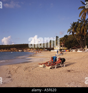 Mittleren gealterten paar entspannen Sie sich in der späten Nachmittagssonne auf einer ruhigen Gegend, selbst am Dickenson Bay Beach Antigua Karibik Stockfoto