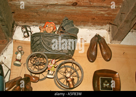 Einem alten Kinderwagen mit einer Quasimodo Puppe in einem Antiquitätengeschäft und Schuh hält an der Wand hängend Stockfoto