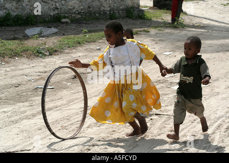 Kinder drehen einen Reifen auf einem Feldweg, Stonetown, Sansibar, Tansania Stockfoto