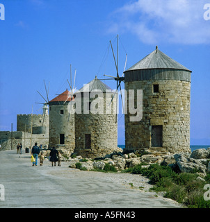 Reihe von drei Runden alten Stein gebaut Windmühlen mit Festung Turm und Leuchtturm jenseits am Mandraki Hafen Rhodos griechische Inseln Stockfoto