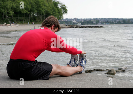 passen Sie, männliche Ausübung erstreckt sich vom Ozean Stockfoto