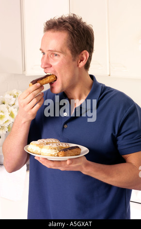 MANN IN DER KÜCHE ESSEN SAHNE KUCHEN Stockfoto