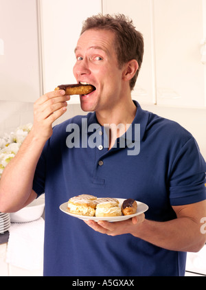 MANN IN DER KÜCHE ESSEN SAHNE KUCHEN Stockfoto