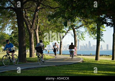 ILLINOIS-Chicago-Läufer und Radfahrer nutzen gepflasterten Weg zwischen Bäumen entlang Seeufer auf Sommer morgen Skyline im Abstand Stockfoto