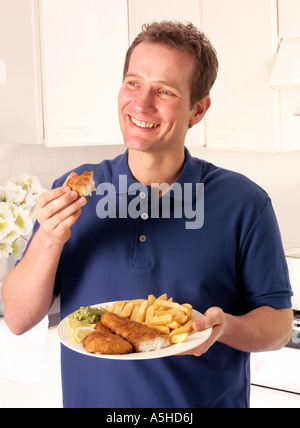 MANN IN DER KÜCHE ESSEN ANGELN UND CHIPS Stockfoto