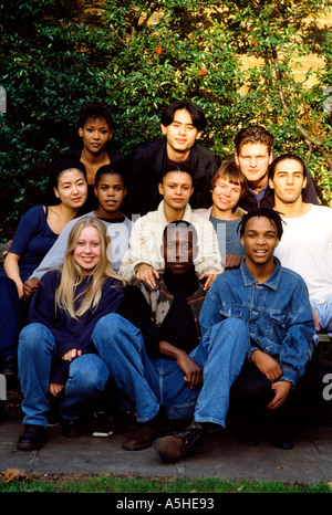 Eine Gruppe von jungen Menschen verschiedener Rassen, die sitzen in der Sonne, Blick in die Kamera Stockfoto