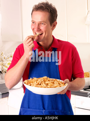 MANN IN DER KÜCHE ESSEN CHIPS Stockfoto