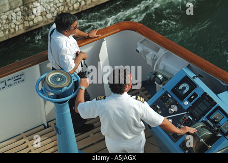 Kreuzfahrt-Schiffskapitän und einheimischen Lotsen an Reglern auf Flügel Brücke Überwachung Seite Triebwerke Dockside Schiff Abkehr Stockfoto