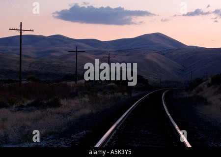 Geschwungene Railroad Tracks Telegrafenmasten bedeckt Beifuß Berge im ländlichen Elko County Nevada USA Stockfoto