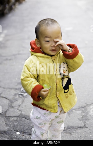 CHINA SHANGHAI chinesische junge Kleinkind in einer hellen gelben und roten Jacke reibt sich die Augen schläfrig Stockfoto