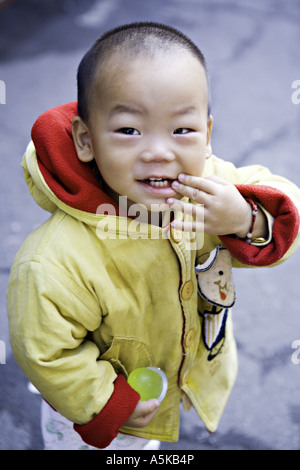 CHINA SHANGHAI chinesische junge Kleinkind in einer hellen gelben und roten Jacke blickt mit Erstaunen Stockfoto