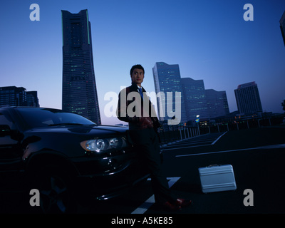 Asiatischer Mann stützte sich auf eine Motorhaube Stockfoto