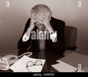 Älterer Mann im Büro sitzt an seinem Schreibtisch besorgt und müde überarbeitete New York USA Stockfoto