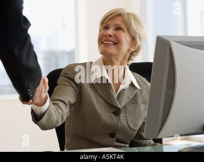 Senior Geschäftsfrau Händeschütteln am Schreibtisch Stockfoto