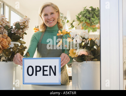 Weibliche Florist hängende Schild im Fenster "geöffnet" Stockfoto